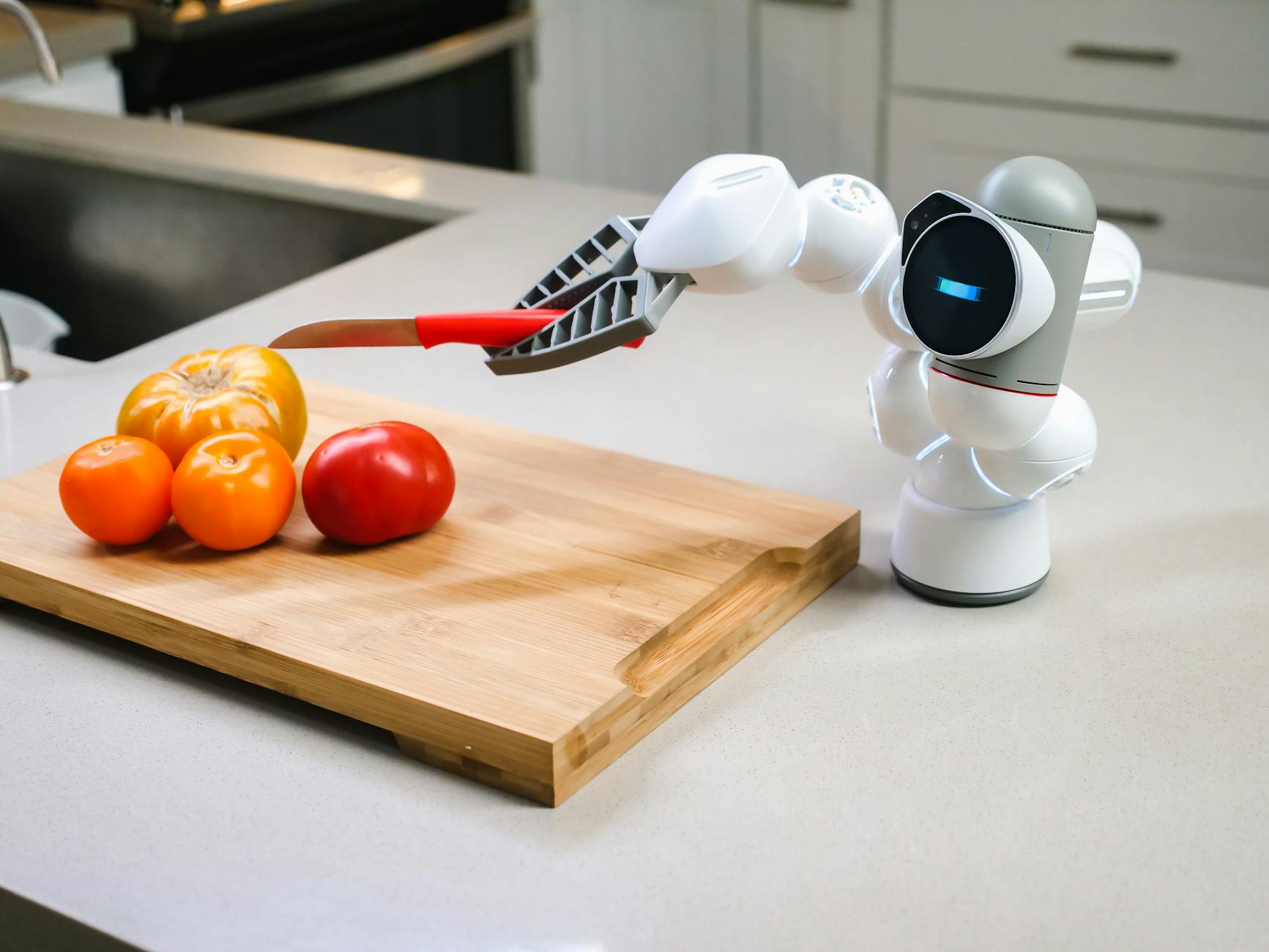 a clicbot about to cut a tomato using a knife
